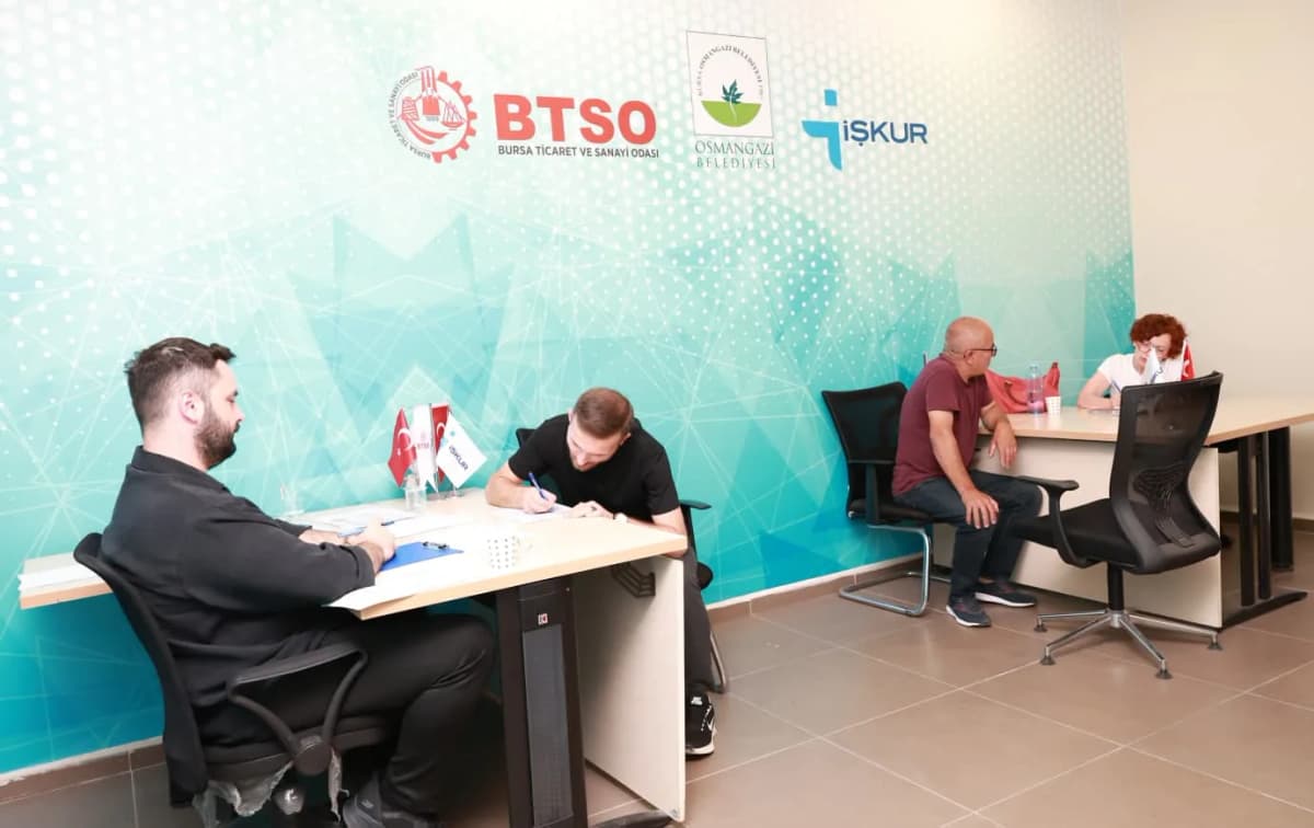 Toplu Görüşme Anı: Bir masa etrafında birden fazla kişi iş başvurusu formu üzerinde çalışıyor.