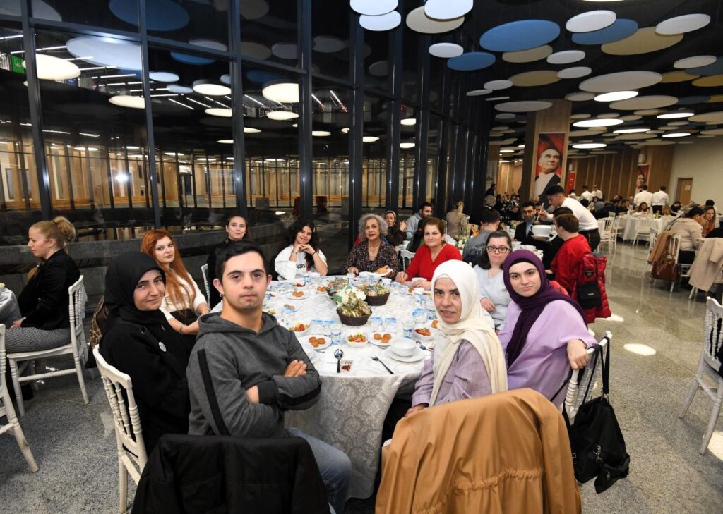 Osmangazide düzenlenen dünya engelliler günü programına katılan engelli bireyler ve ailelerinin geniş masa etrafında birlikte görünümü